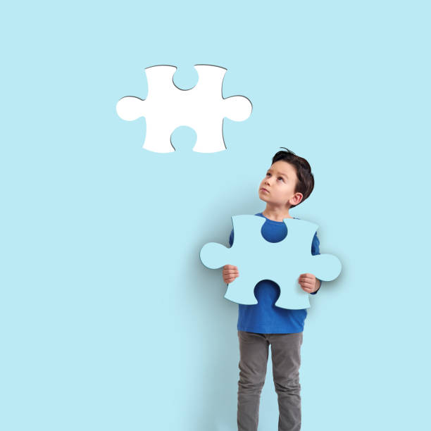 6-7 years old child holding puzzle piece on blue background. His piece complete missing piece on wall.