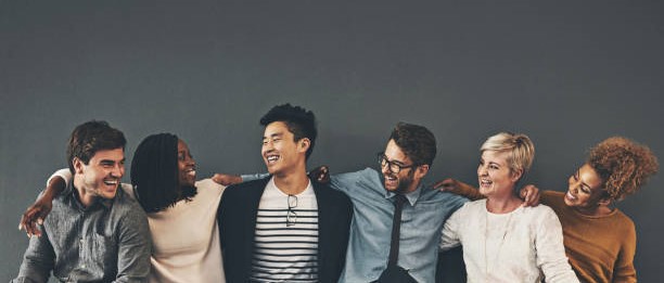 Studio shot of a diverse group of creative employees embracing each other against a grey background